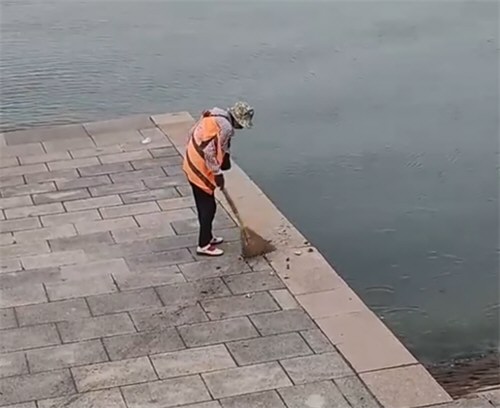 青岛一环卫工人将垃圾扫进大海