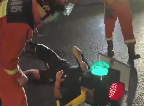 男子骑车玩手机致脑袋卡进红绿灯